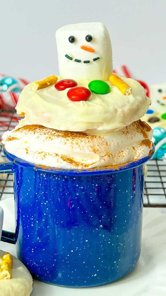 Melted snowman peanut butter cookies in a blue mug of hot cocoa.