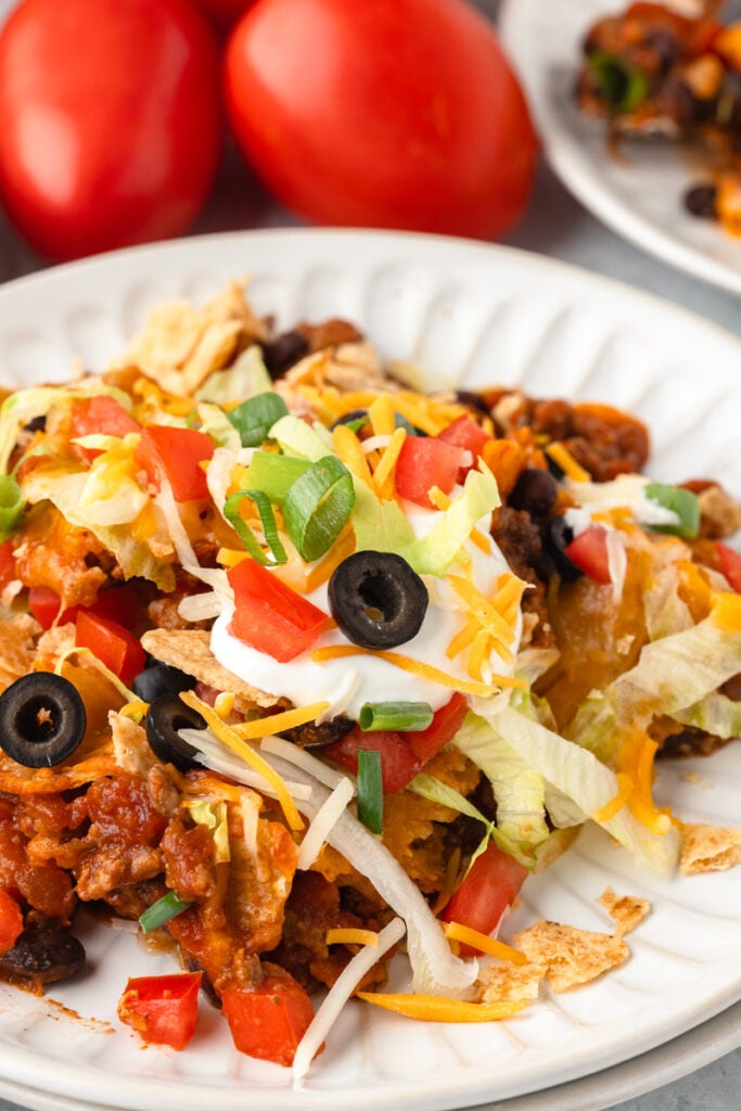 Serving of taco casserole recipe with ground beef on white plate.