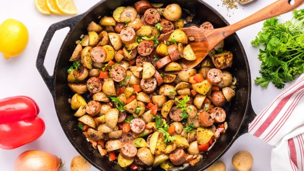 Skillet sausage and potato with wooden spoon.