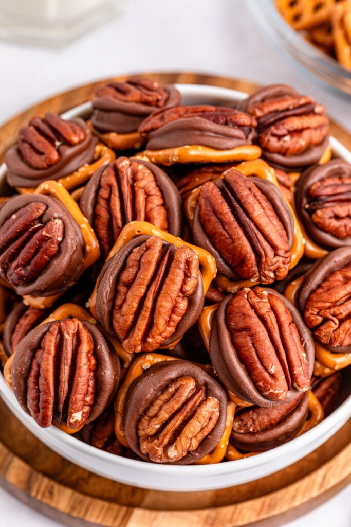Pecan turtle pretzel bites in a white bowl.
