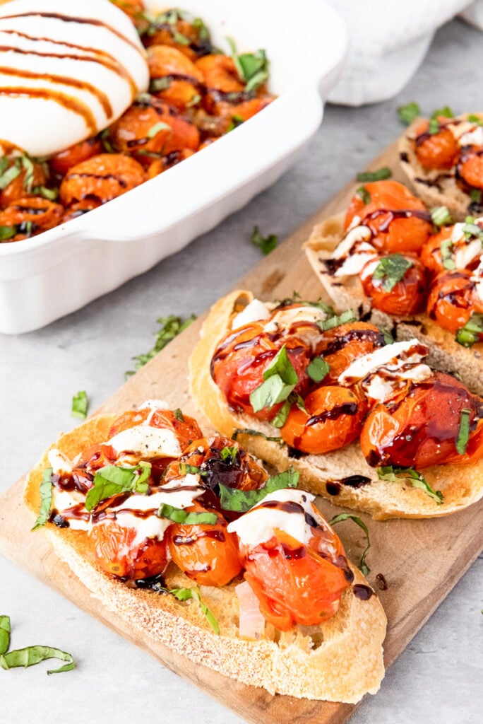 Roasted tomato and burrata crostini on a charcuterie board.