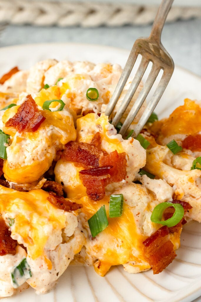Loaded cauliflower casserole on a white plate.