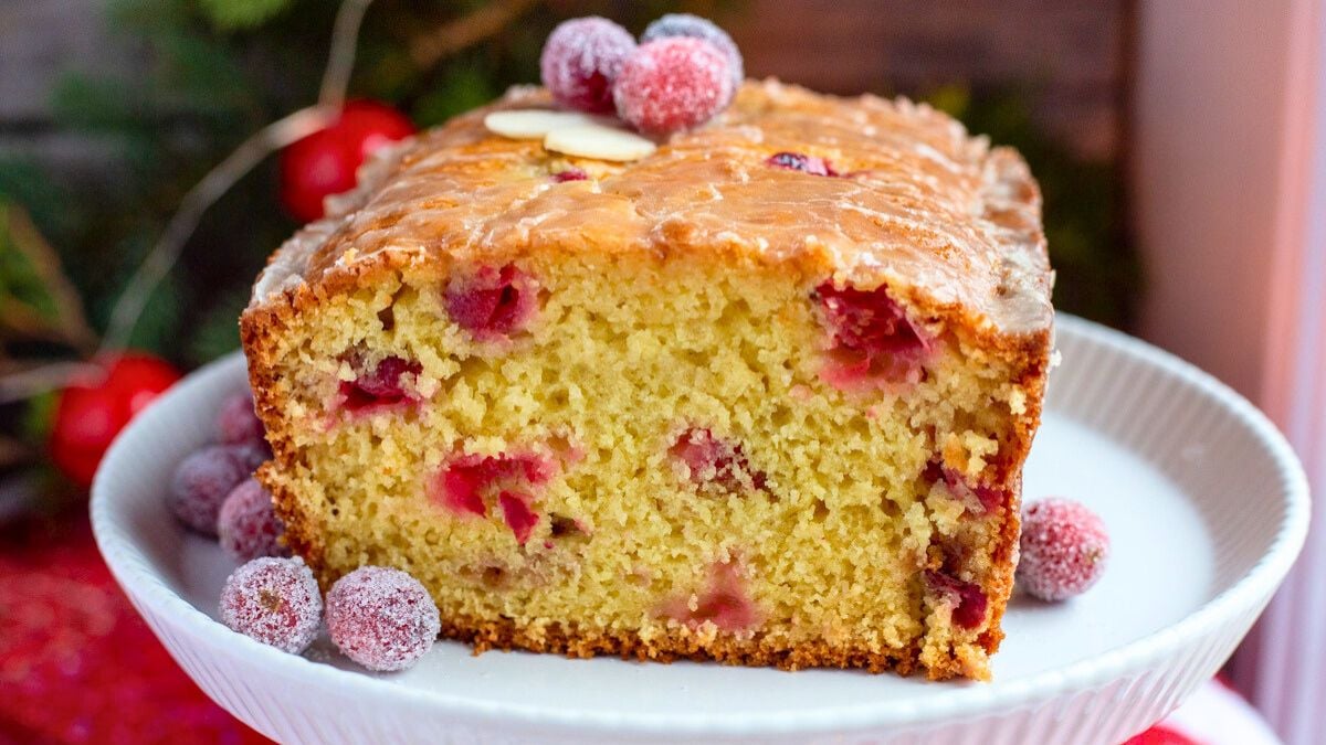 Cranberry orange bread loaf cake with one piece removed.