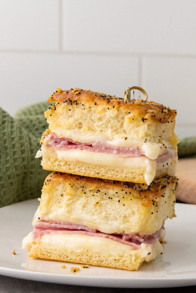 Ham and cheese sliders served on a white plate.
