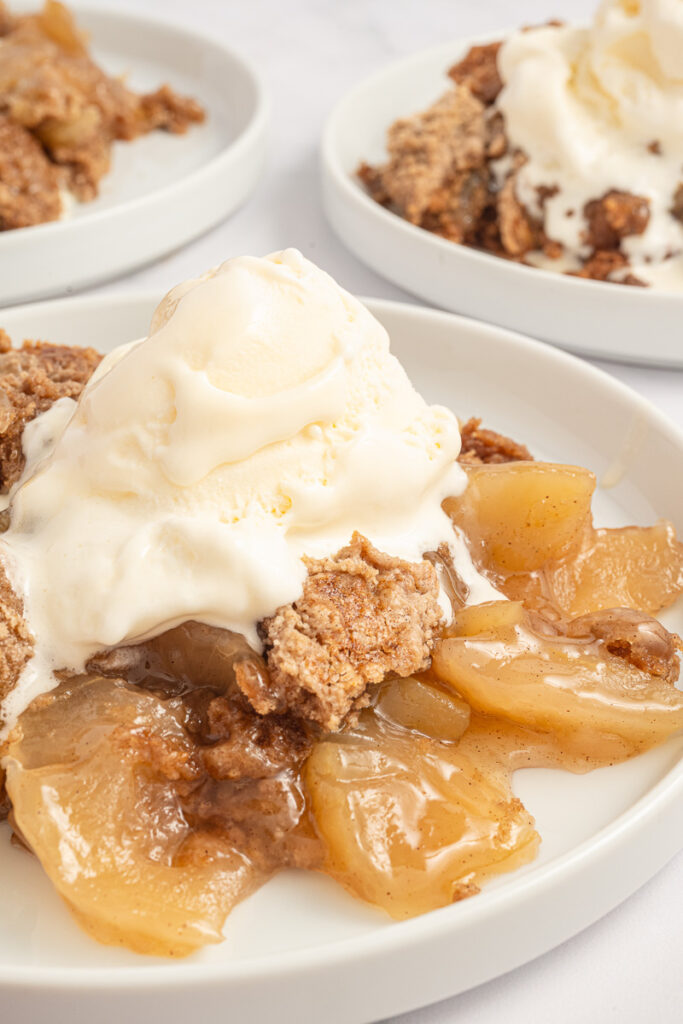 Apple dump cake served on a white plate with vanilla ice cream.