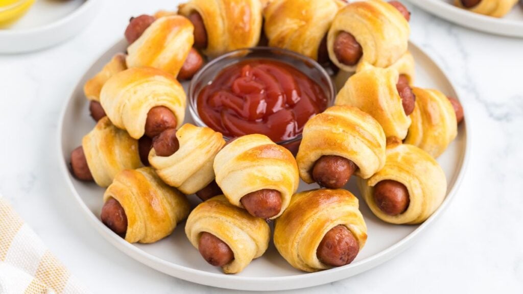 Pigs in a blanket appetizers on a white plate.