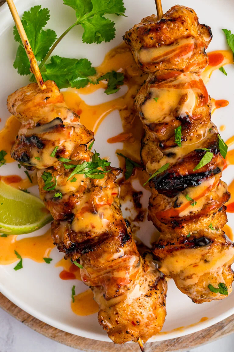 Bang bang chicken skewers served on a white plate.