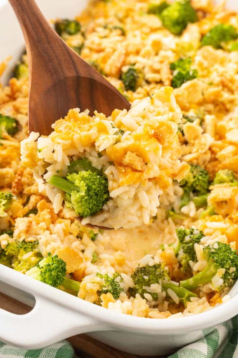 Broccoli rice and cheese scooped up on a spoon held over casserole dish.
