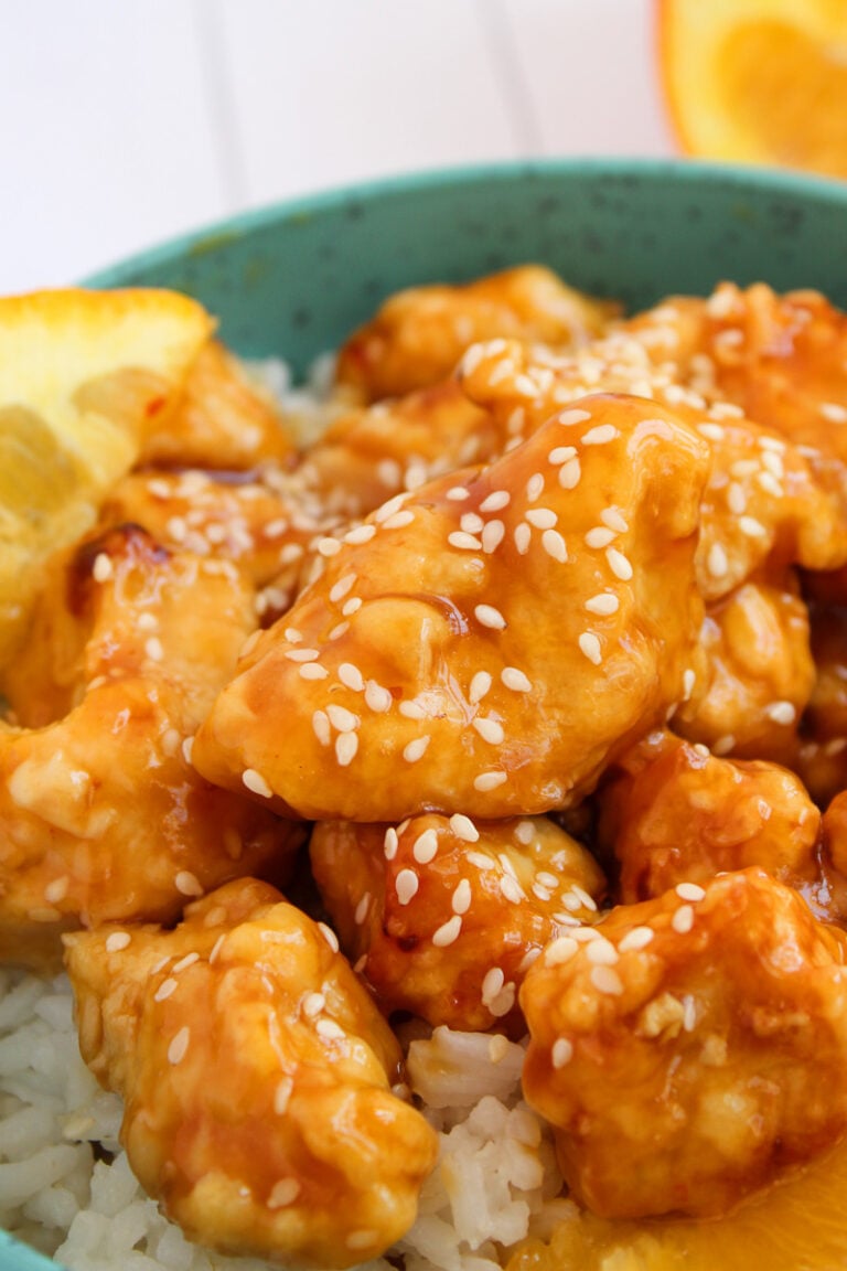 Orange chicken on a bed of white rice on a plate.
