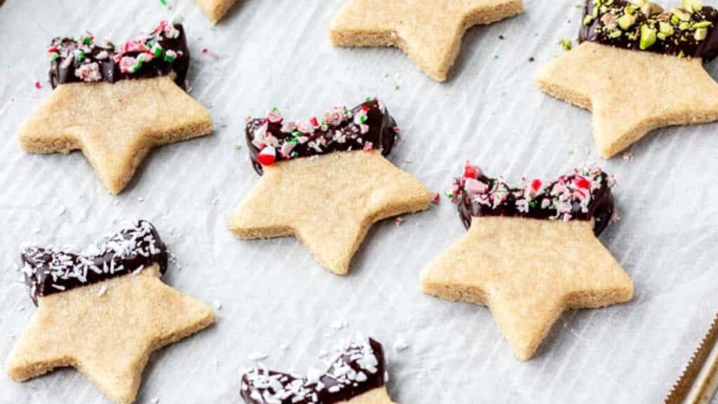 Chocolate-dipped star shaped Christmas cookies on a white plate.