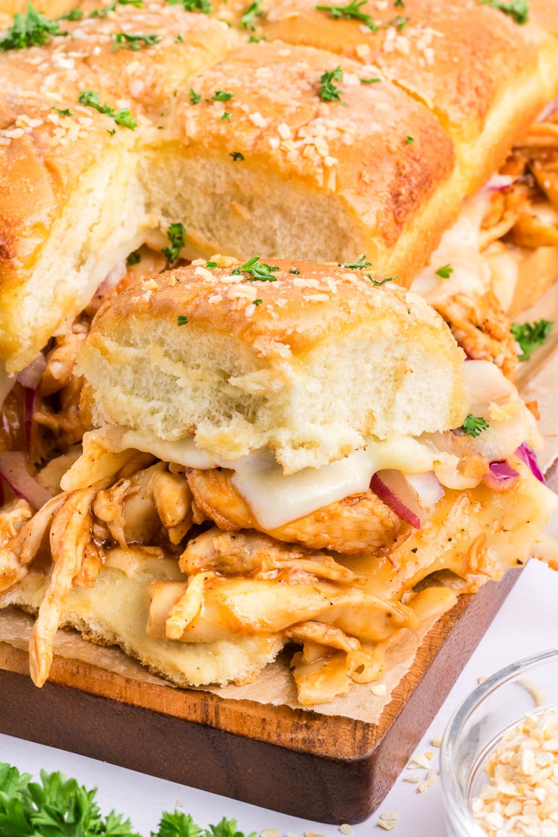 BBQ chicken sliders on a wooden board.