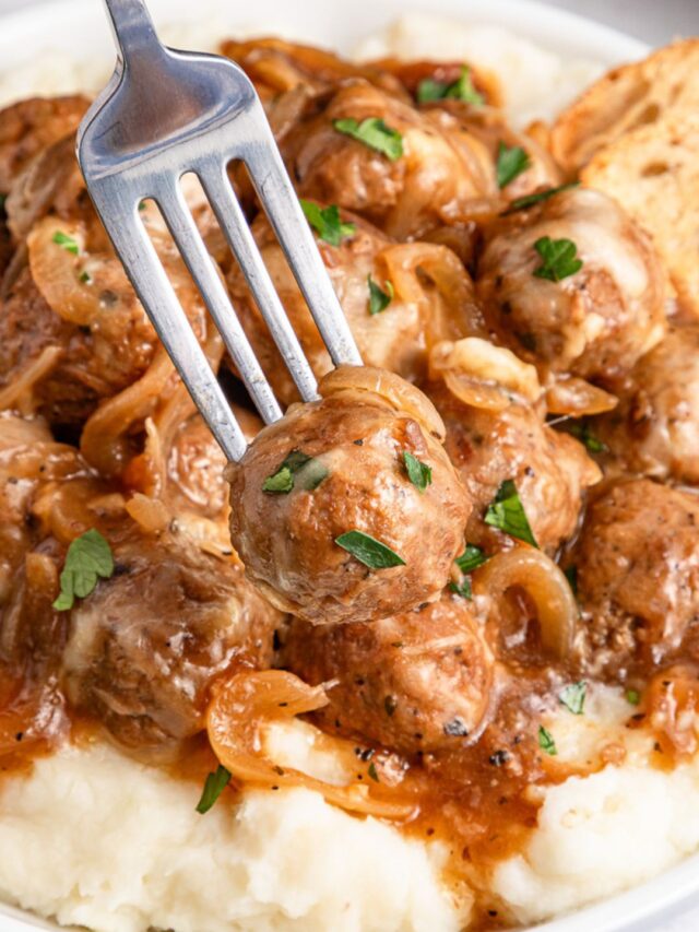 French onion meatballs on a bed of mashed potatoes on a plate.