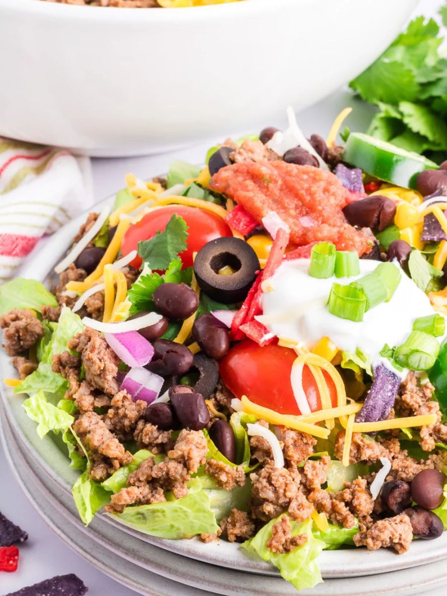 Taco salad with ground beef in a white bowl.