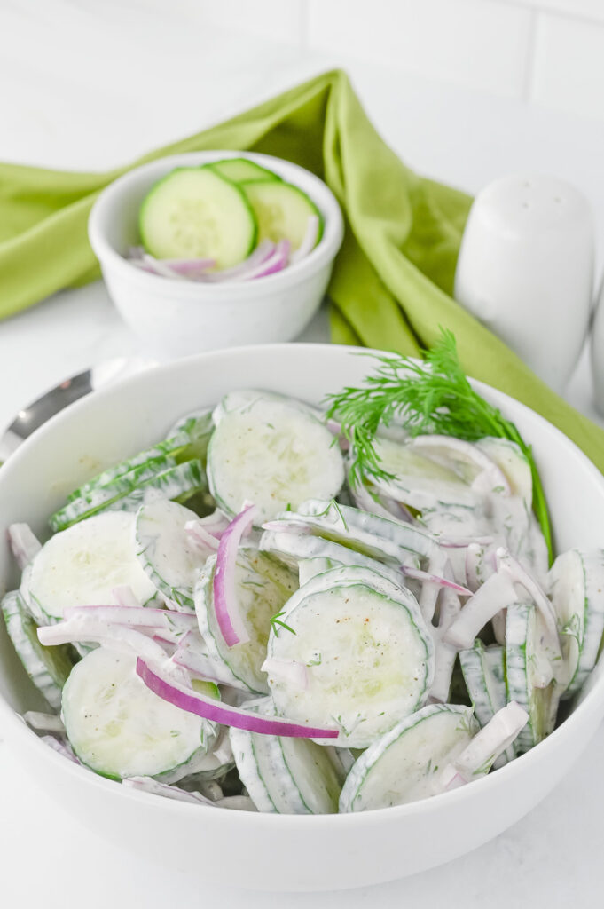Creamy cucumber salad in a white bowl.