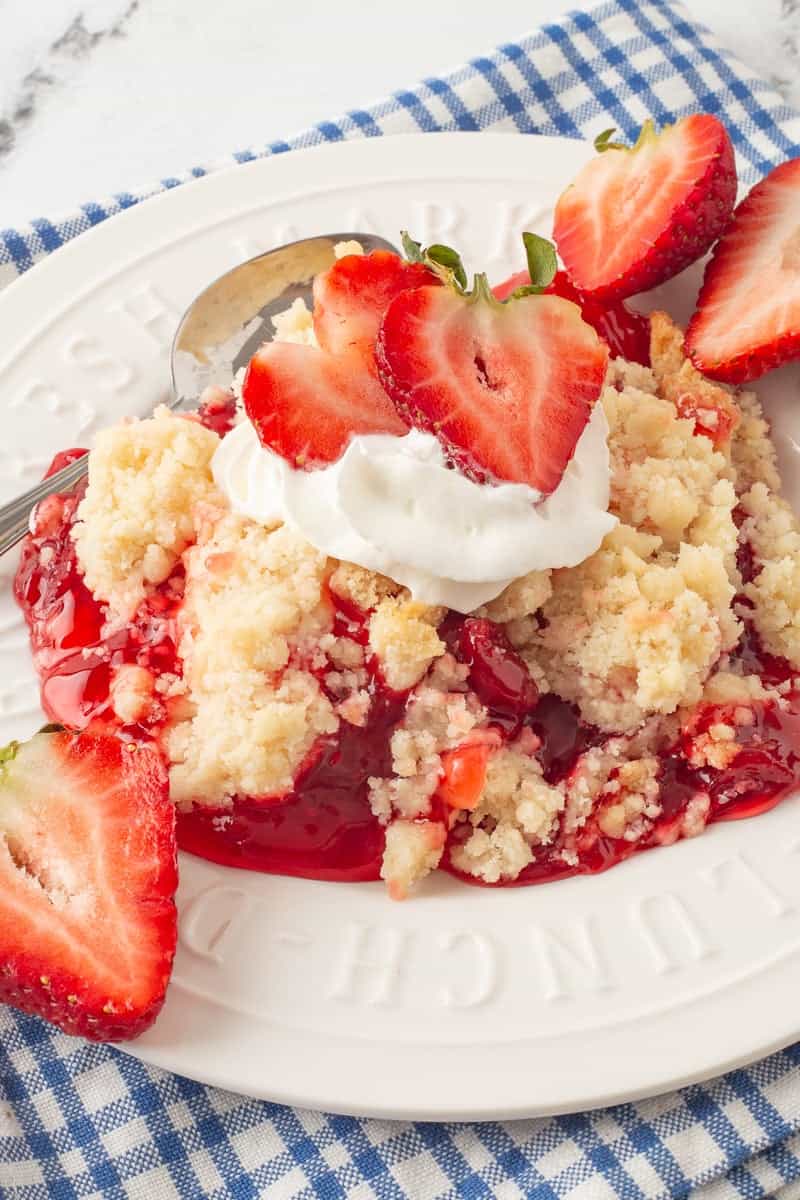 Strawberry dump cake on a white plate with a spoon.