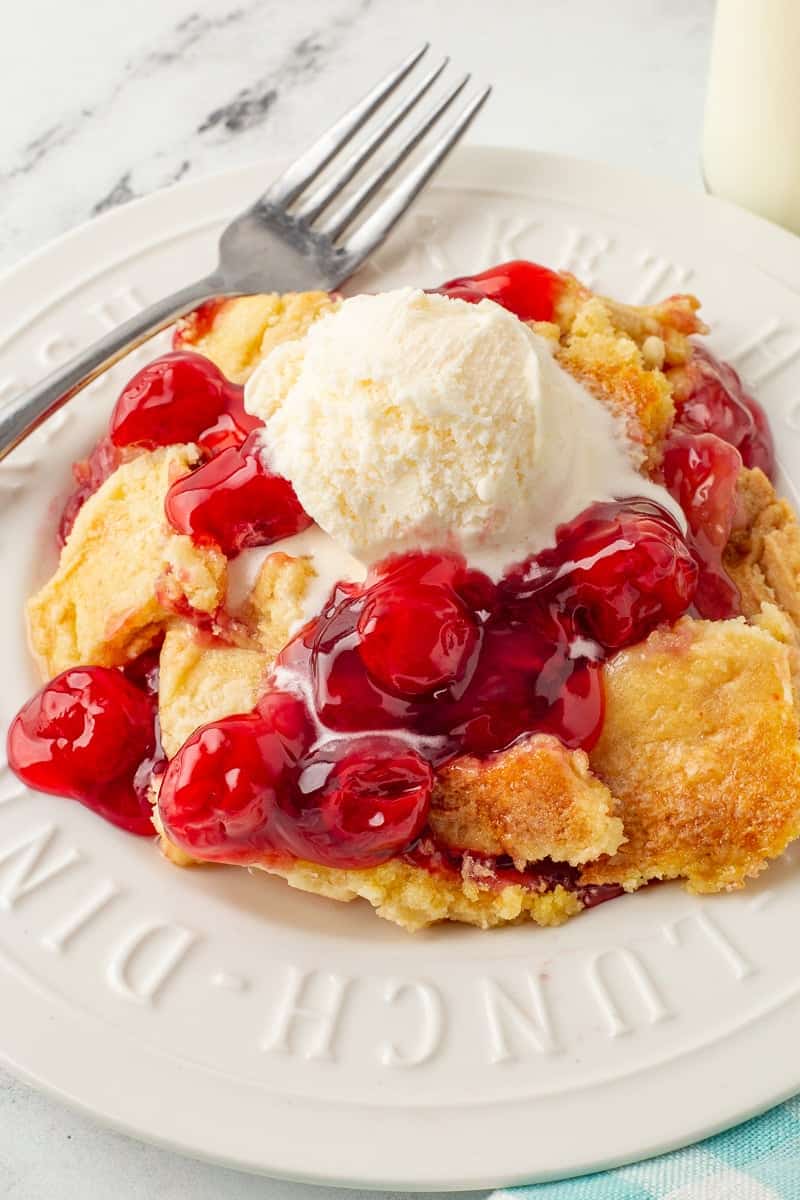 Cherry pineapple dump cake on a white plate.