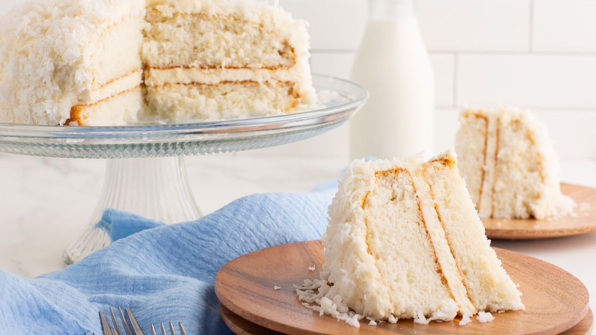 Coconut cake served on a plate with remaining cake in background.