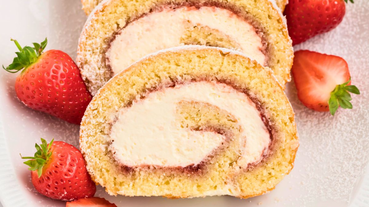 Strawberries and cream swiss roll on a plate.