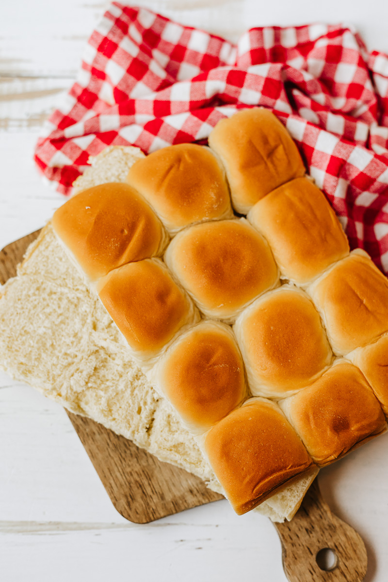 Sliced Hawaiian roll sliders on a wooden cutting board.