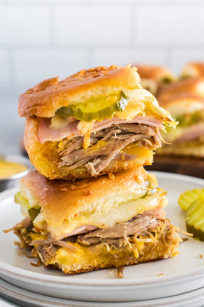 Cuban sliders stacked on a white plate.