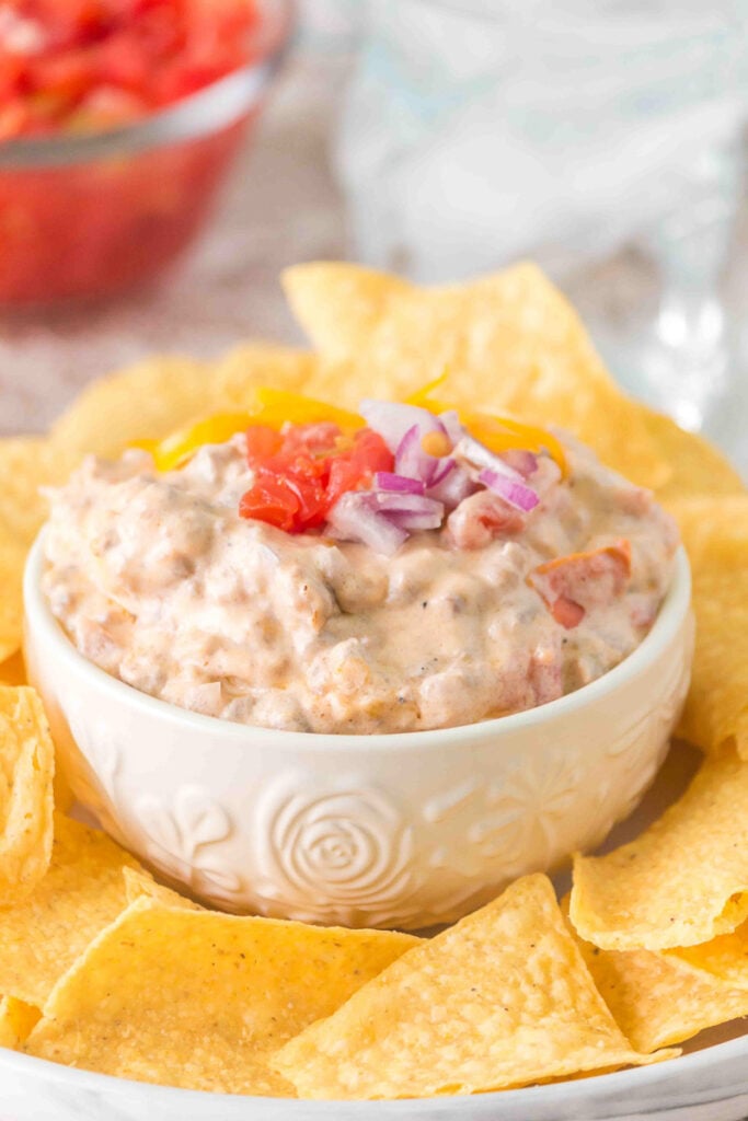 Rotel dip with ground beef in bowl with nachos on the side.