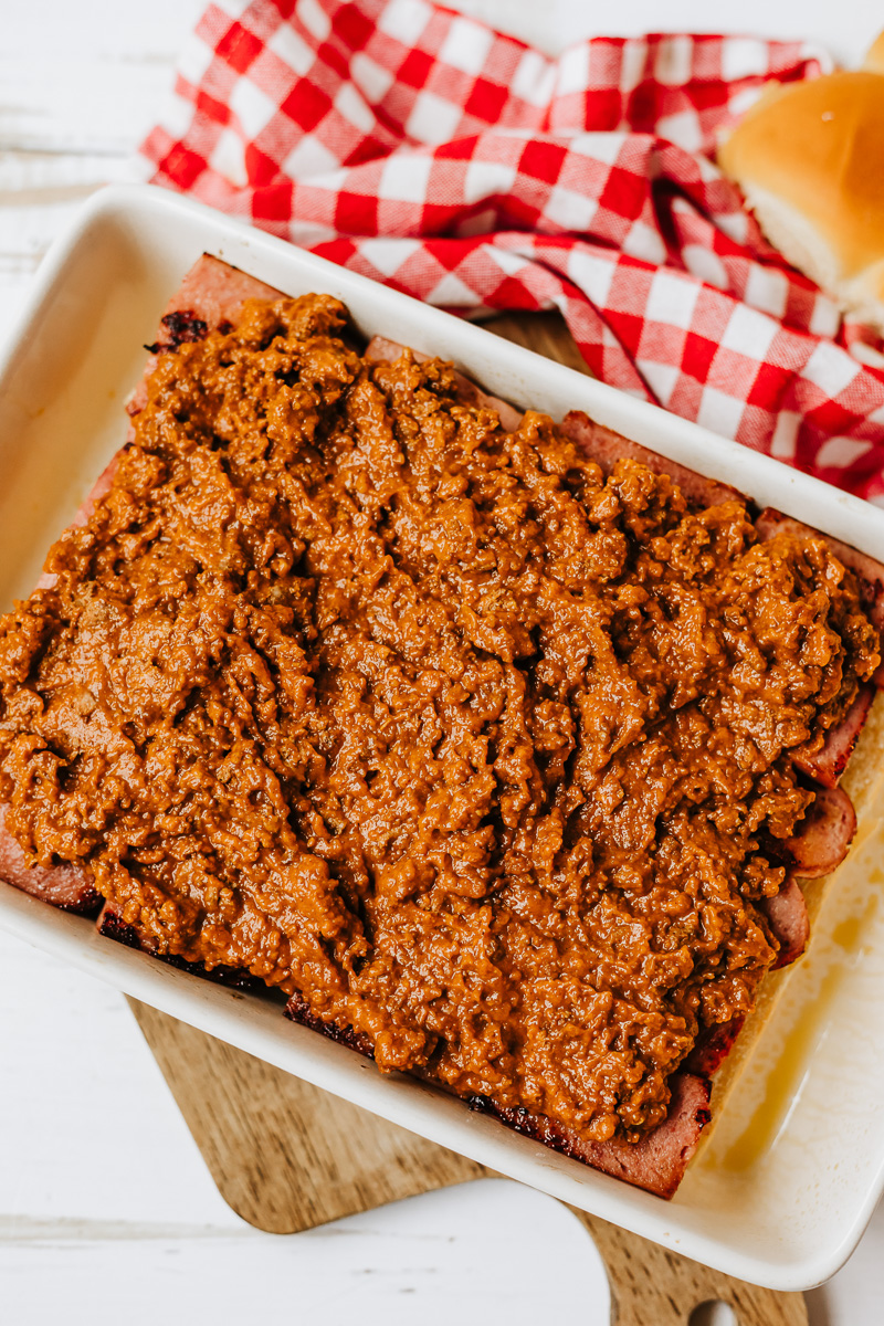 Chili is spread on top of sausage.