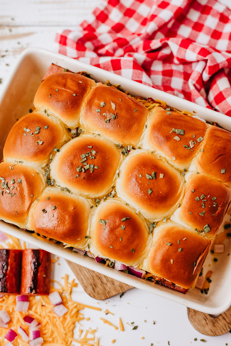Baked chili cheese dog sliders overhead view in baking dish.
