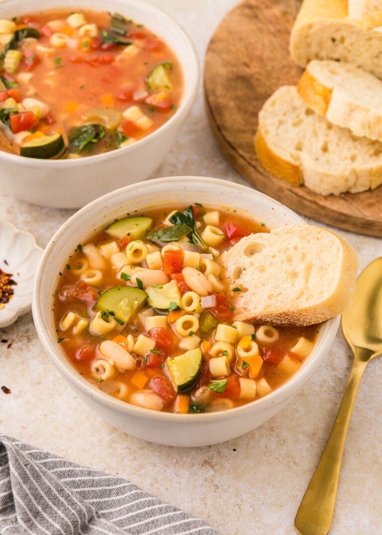 Minestrone soup served in bowl with crusty bread on the side.