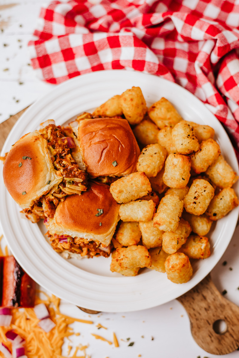 Overhead view of chilli cheese dog siders on a plate with tater tots.
