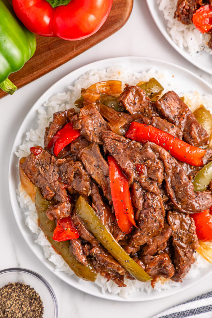 Overhead view of slow cooker pepper steak on a plate with rice.