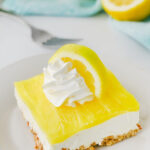 Lemon pretzel salad served on a plate with whippe topping and lemon garnish.