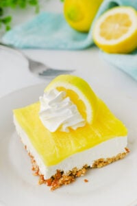 Lemon pretzel salad served on a plate with whippe topping and lemon garnish.