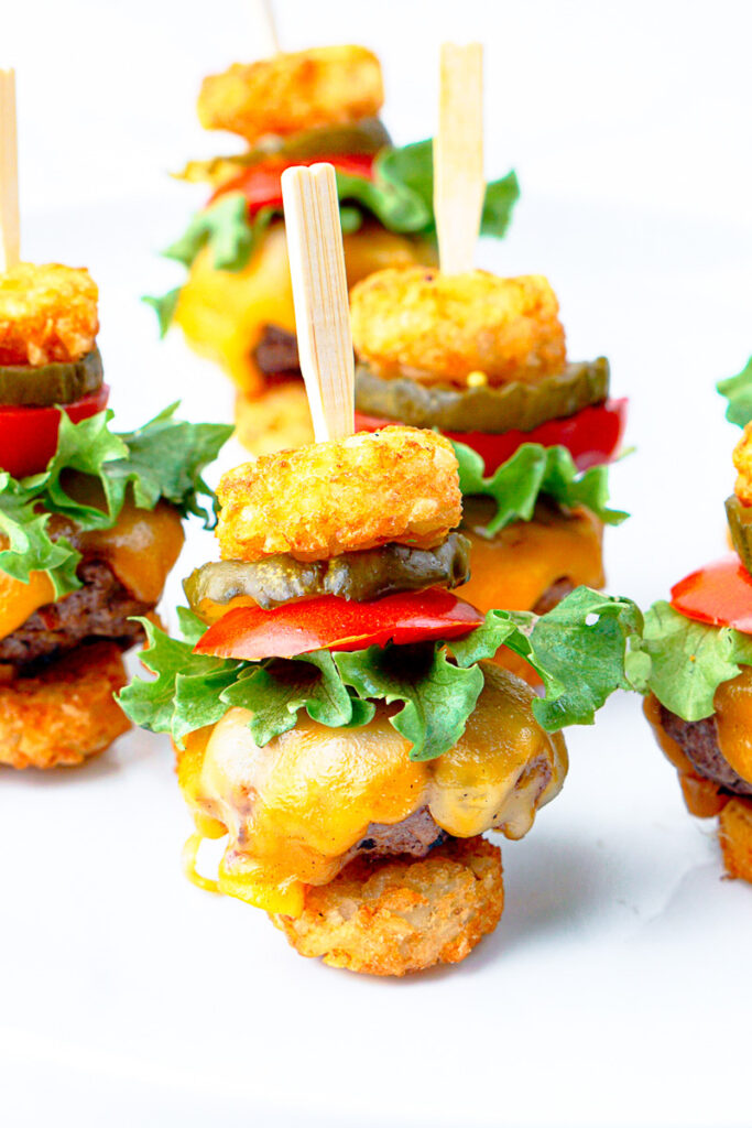 Tater tot mini cheeseburgers on a white plate.