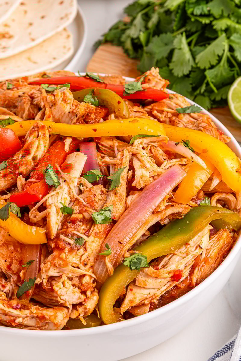Chicken and pepper mixture in white bowl for fajitas.