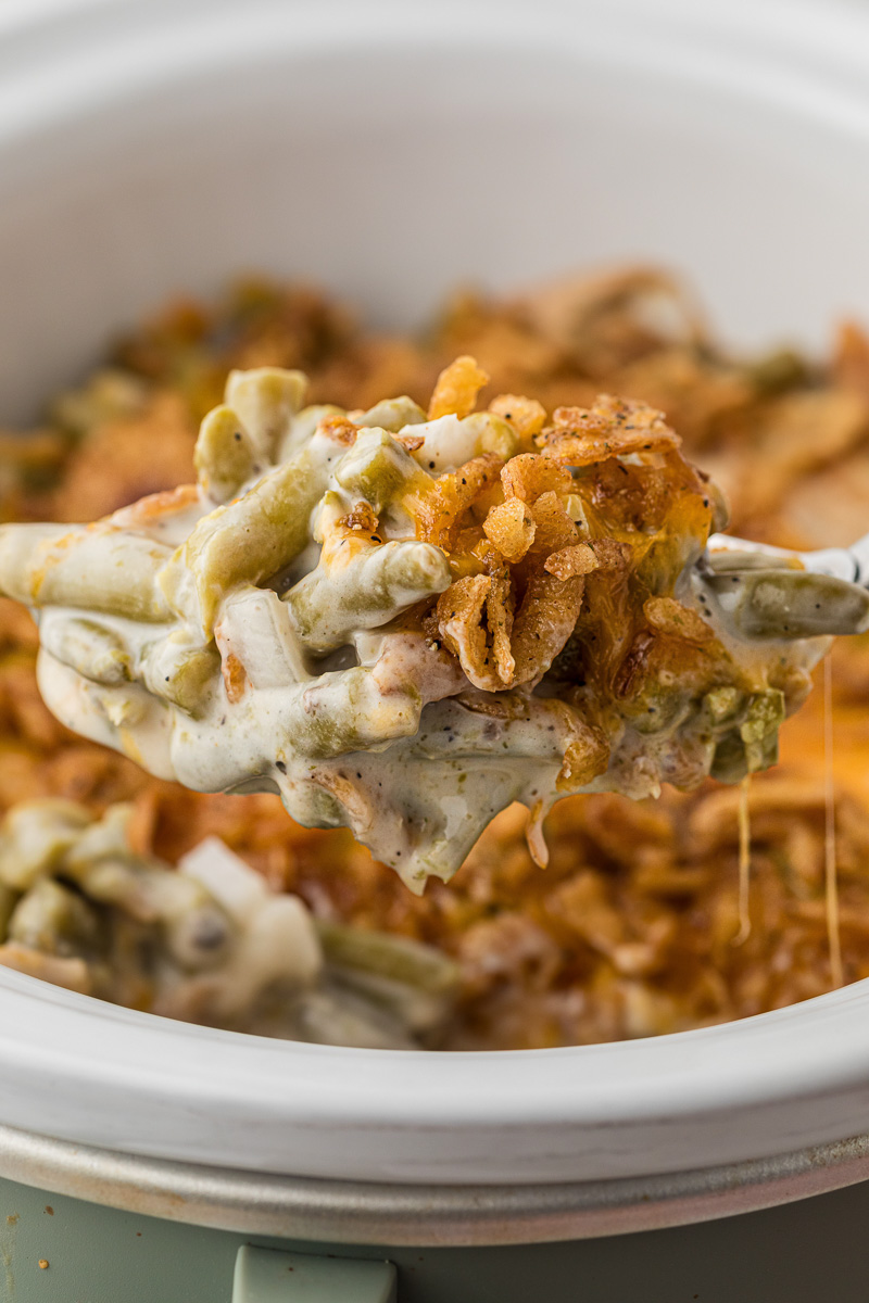 Slow cooker green bean casserole scooped up on spoon.