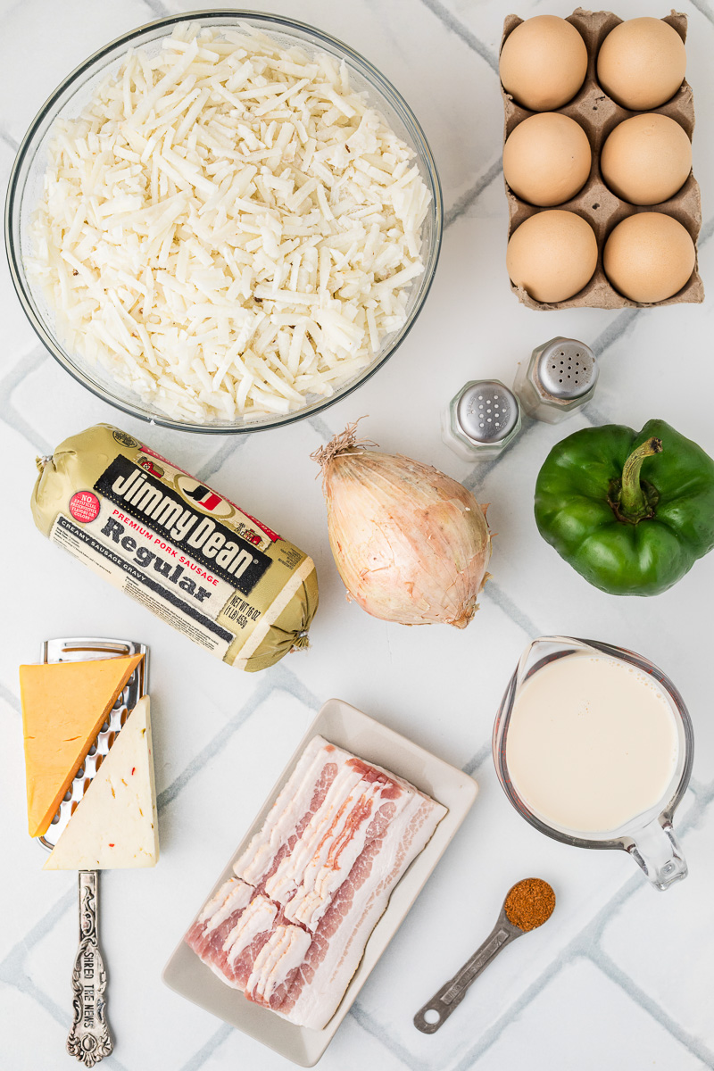 Ingredients for breakfast casserole with hashbrown recipe laid out in small bowls and plate on counter.