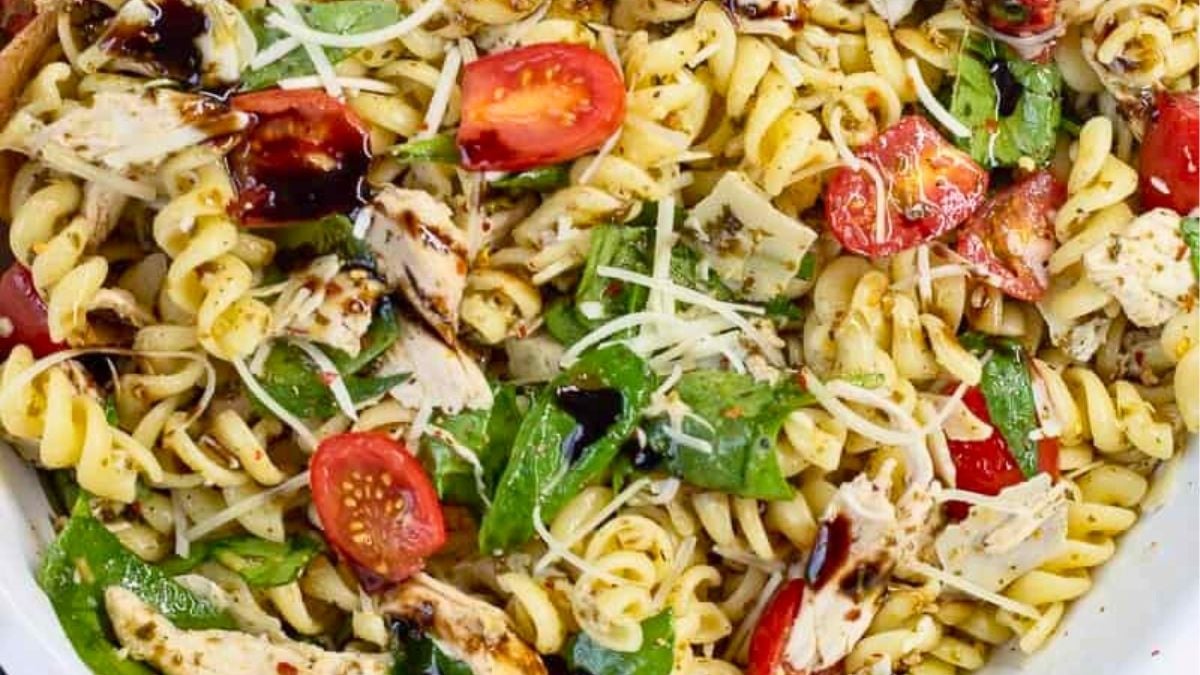 Chicken pasta salad in a white bowl drizzled with balsamic glaze.