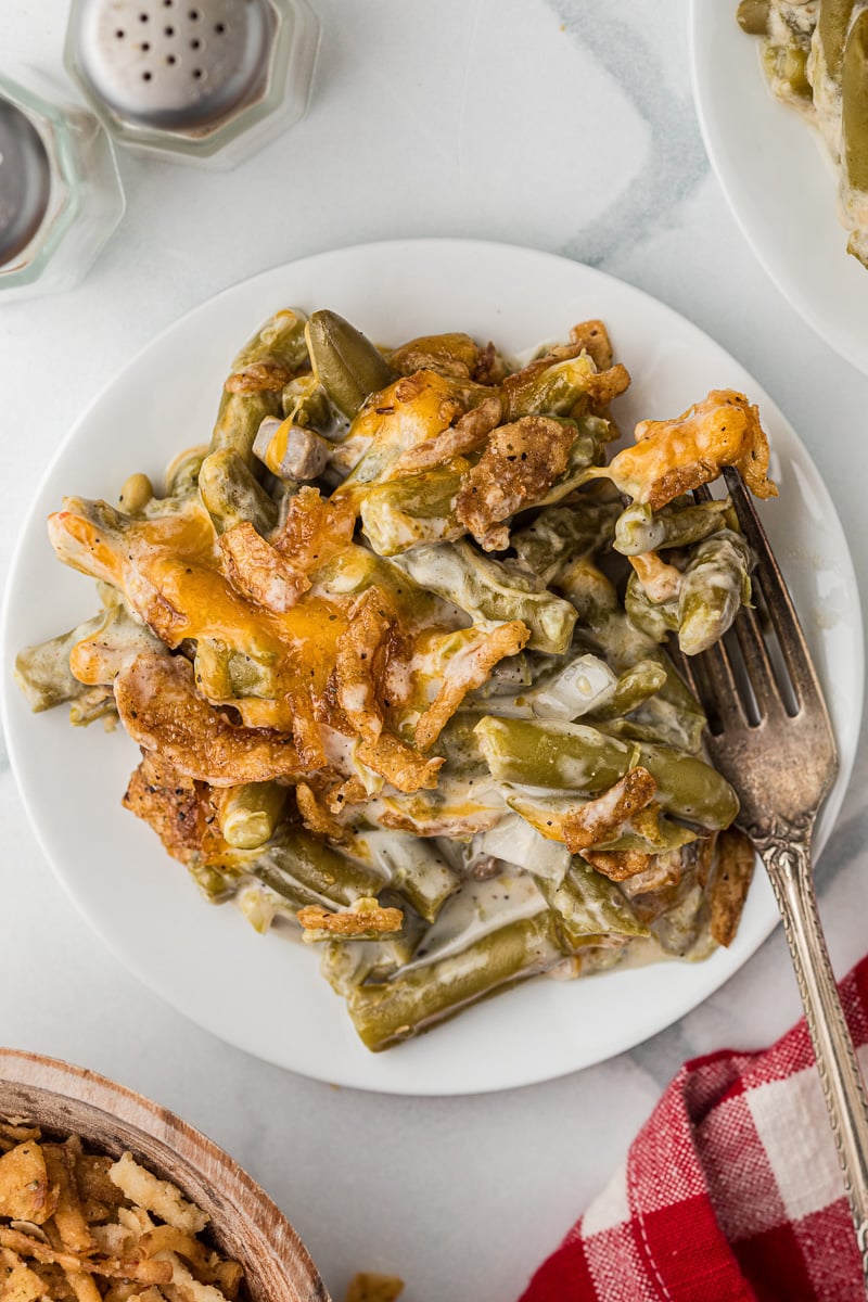 Serving of green bean casserole with crispy onions on a white plate.
