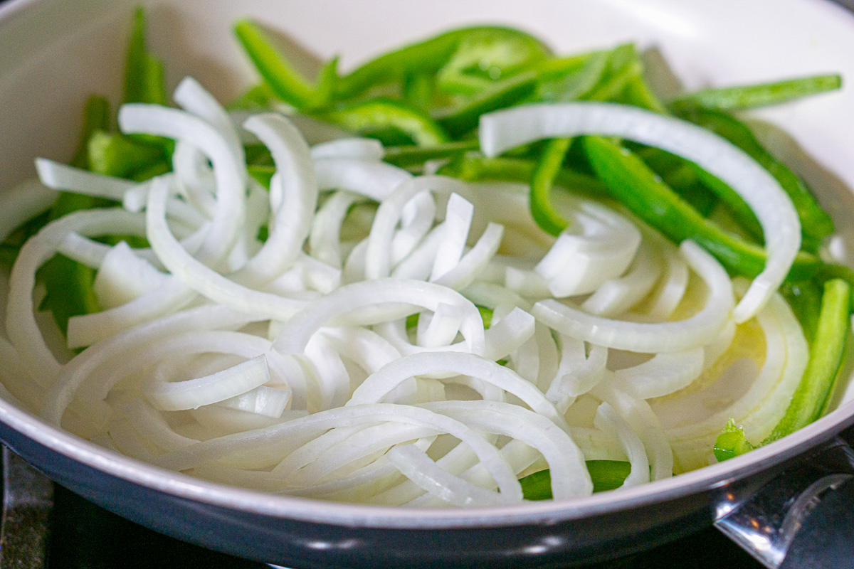 Sliced onions and green peppers in skillet.