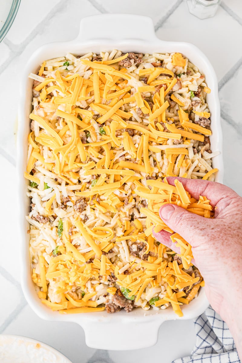 Cheddar cheese is sprinkled on top of baking dish before baking.