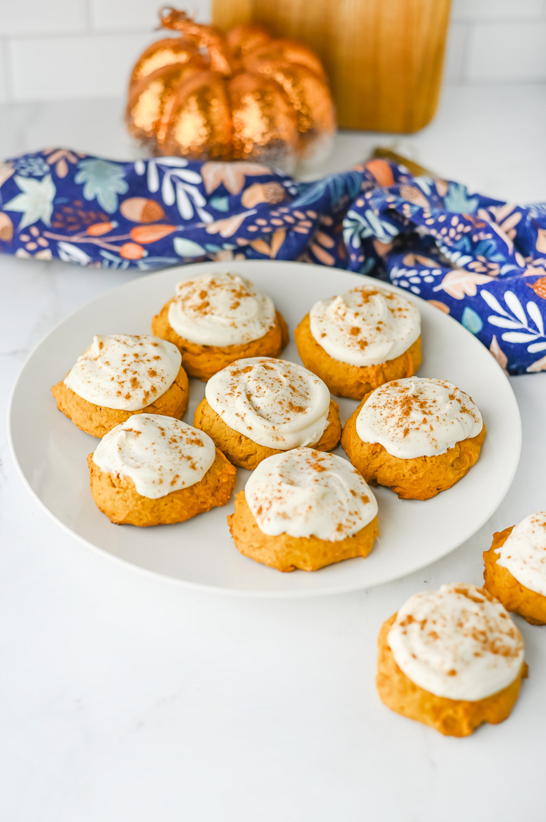 Frosted pumpkin cookies on a white plate.