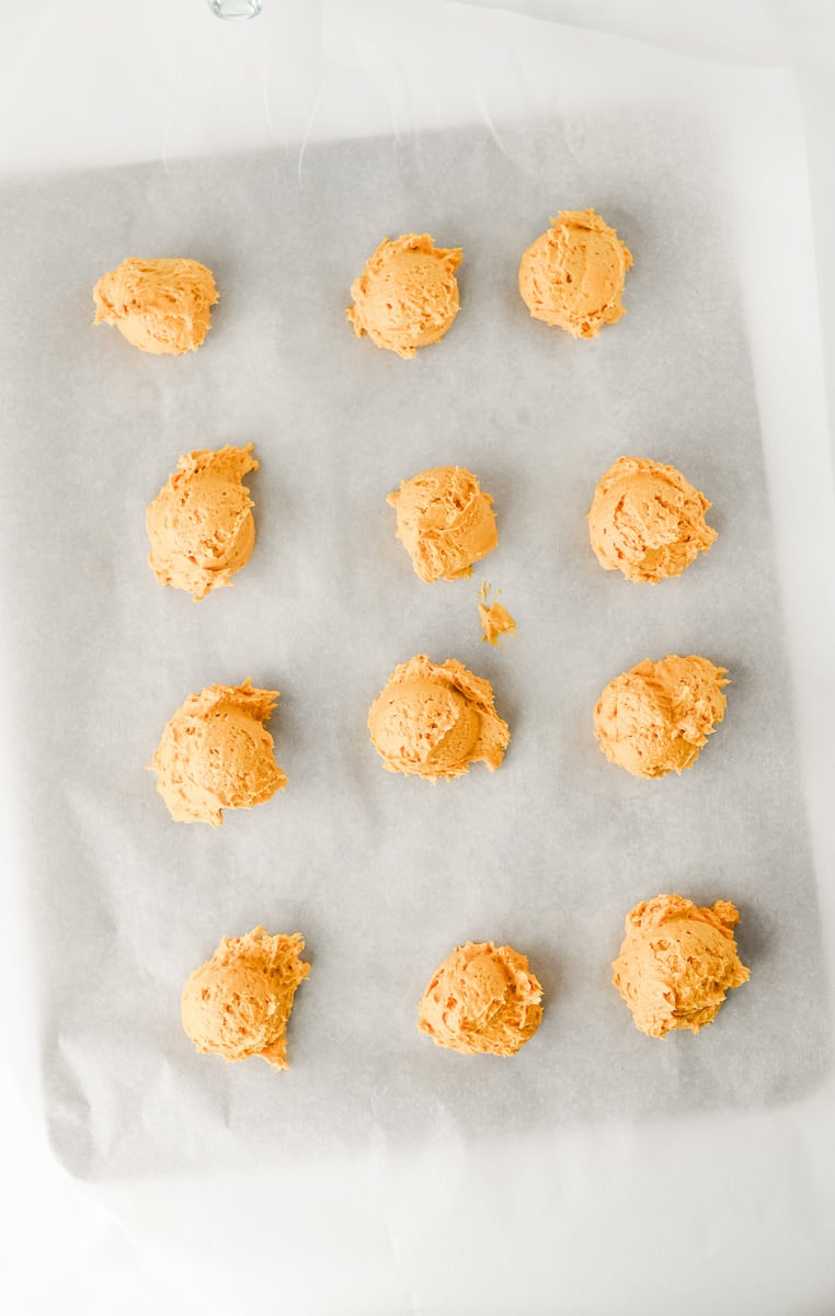 Pumpkin cookie dough balls dropped onto baking sheet lined with parchment paper.