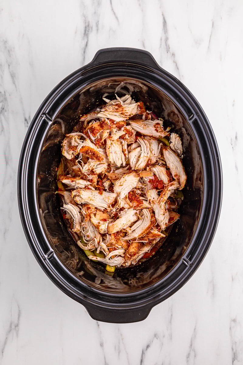 Cooked chicken is shredded, then returned to crockpot.