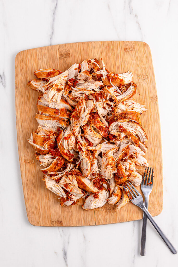 Shredded chicken on cutting board.