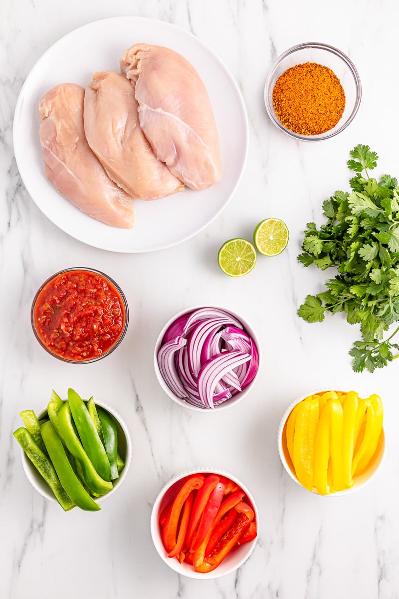 Ingredients for crockpot chicken fajitas in small glass bowls on counter.