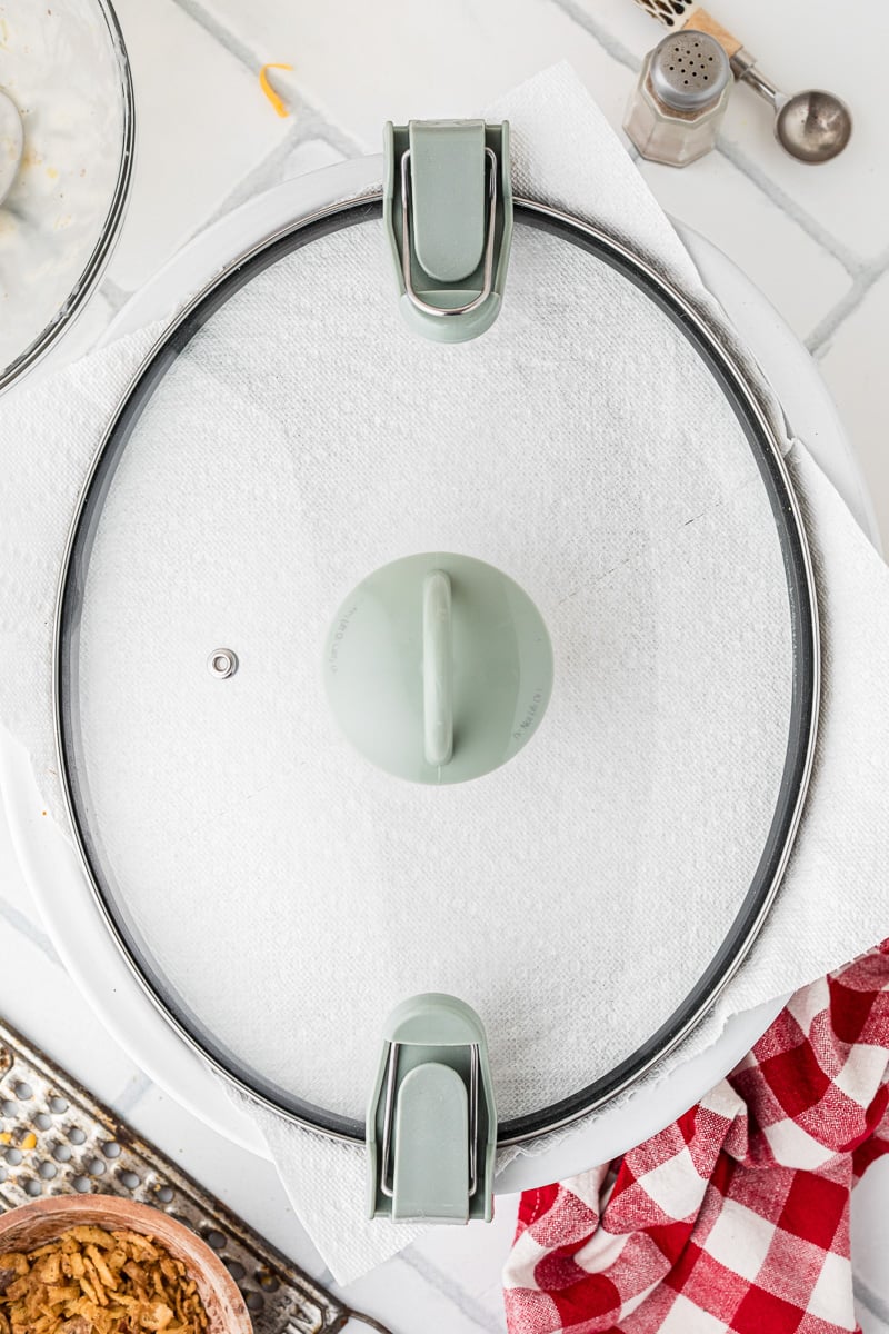 Paper towel is placed across top of slow cooker before covering with lid.
