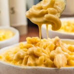 Spoonful of mac and cheese held over bowl.