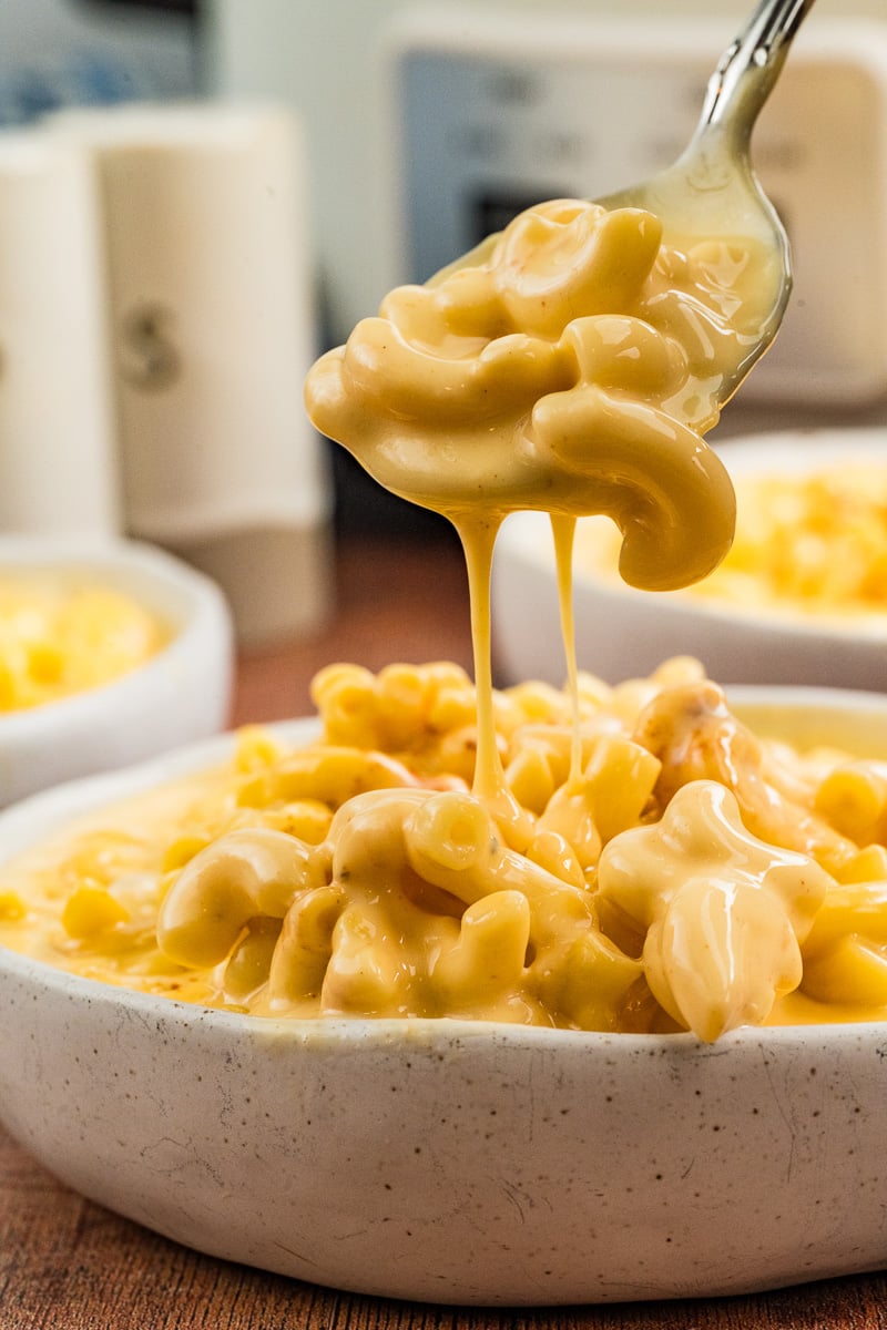 Spoonful of mac and cheese held over bowl.