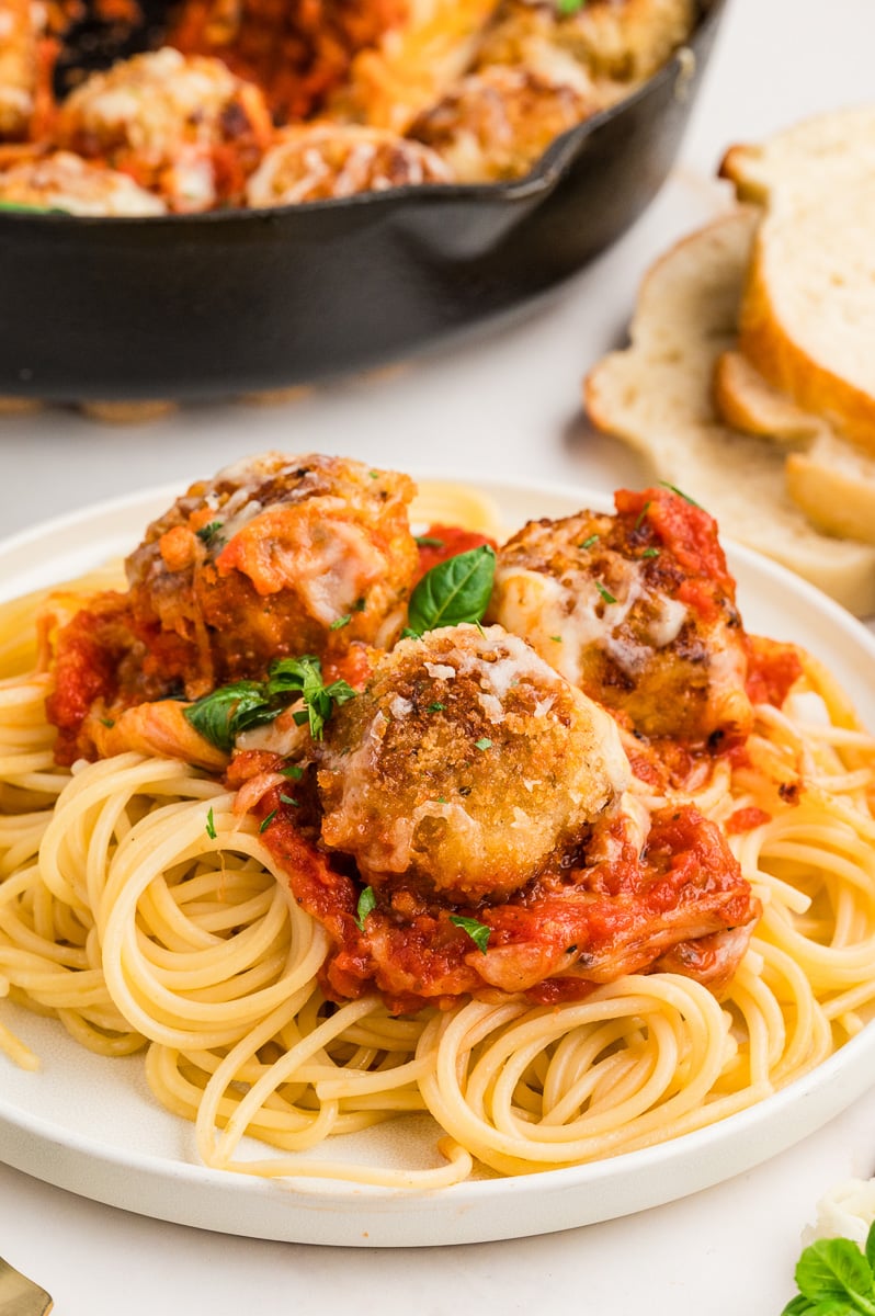 Chicken parmesan meatballs on a plate of spaghetti with marinara sauce.