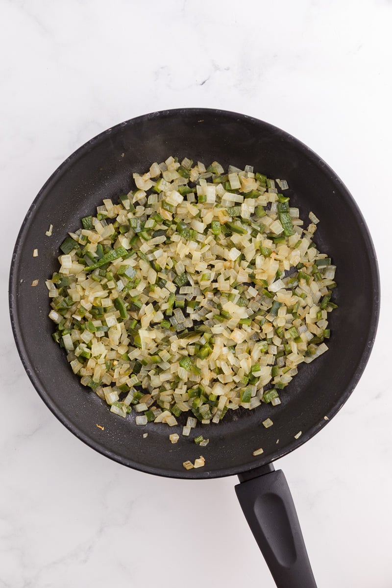Cooked onion and poblano peppers in skillet with olive oil.
